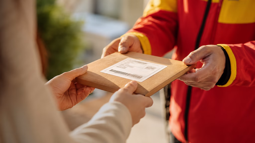 Übergabe eines flachen Versandpaketes durch einen Zusteller. Lieferzeiten