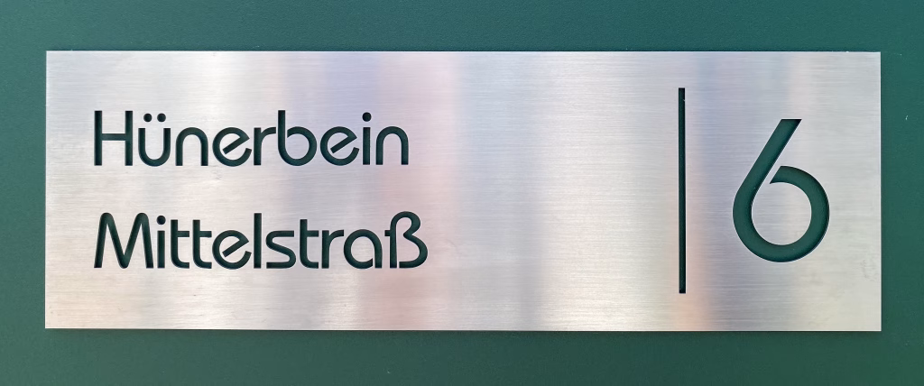 Individuelles Türschild aus gebürstetem Edelstahl mit ausgeschnittenem Namen, Straßennamen und Hausnummer.
